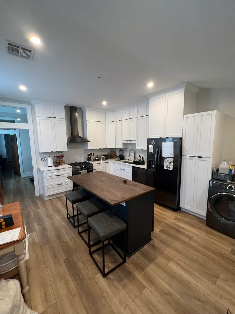 Renovated kitchen with a black island and white perimeter cabinets