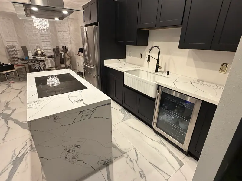 Marble waterfall island beside black cabinets