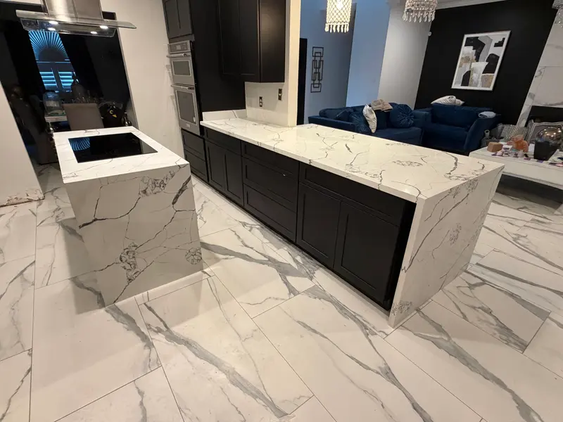 Remodeled kitchen with black cabinets and a marble waterfall island