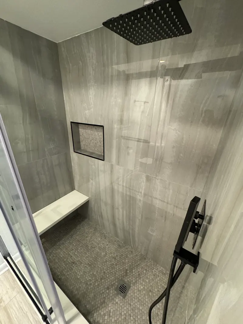 Gray tile shower with a bench and niche